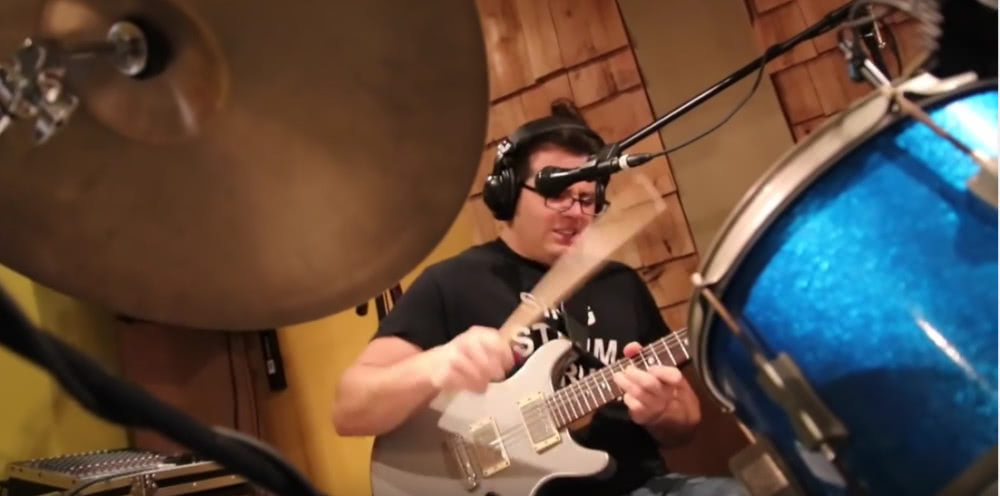 Watch this dude simultaneously play guitars, drums, and sing Rush's