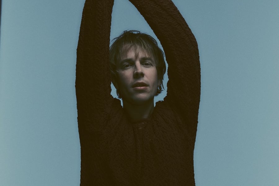 Tom Odell posing with his arms up