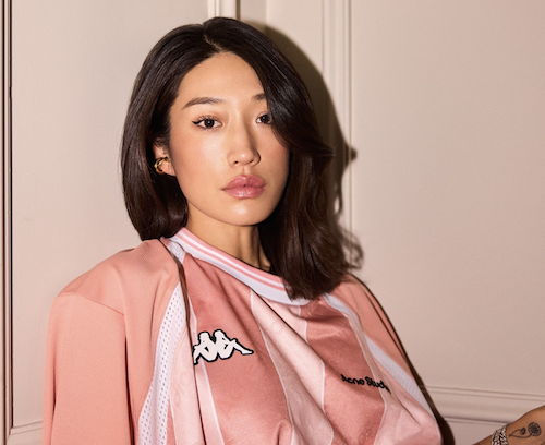 Peggy Gou in a pink shirt looking down the camera