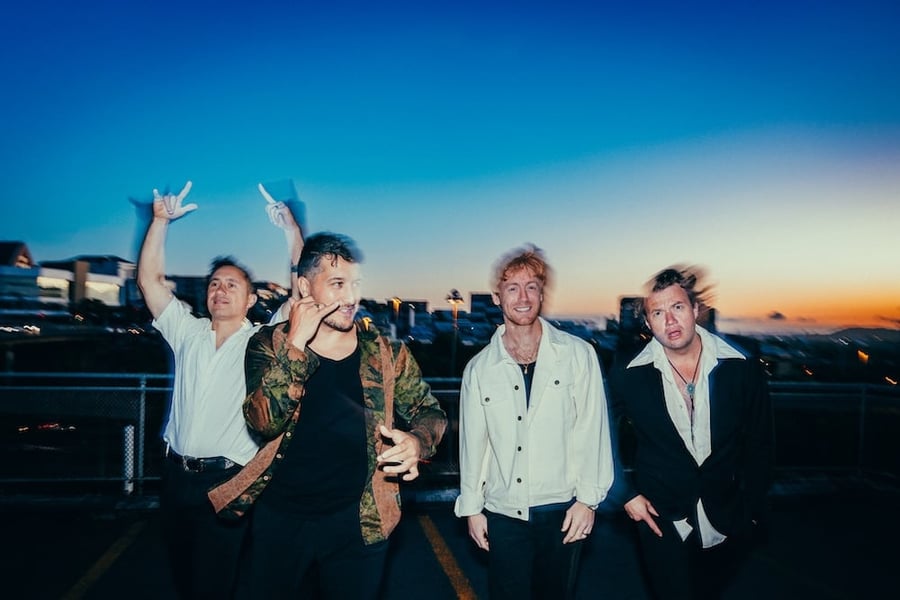 Six60 band mates standing in front of a sunset