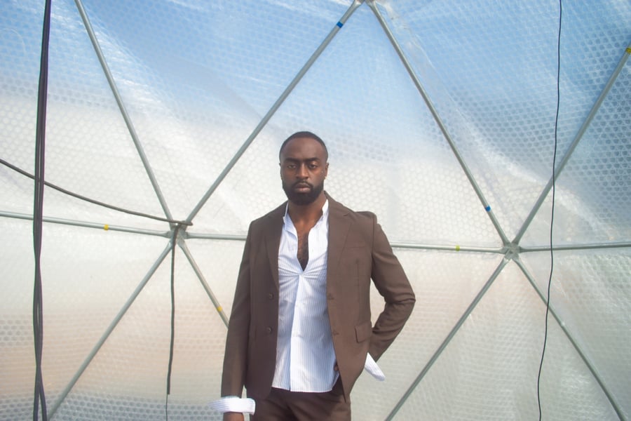 Kwame, real name Rich Amevor, posing wearing a suit jacket
