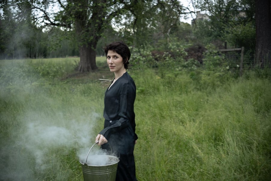 Aldous Harding pictured in a field holding a steaming bucket