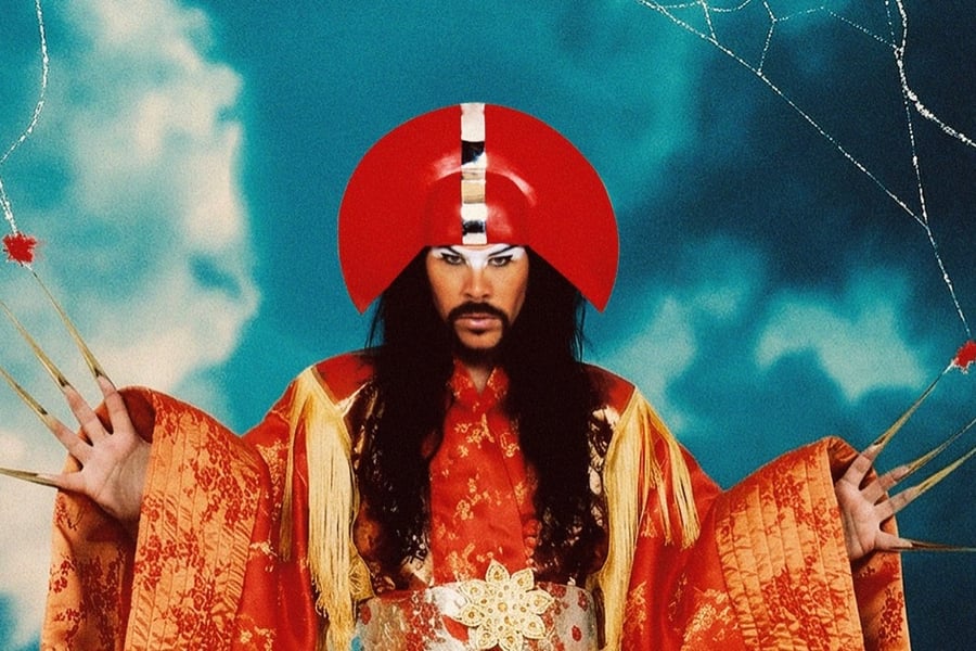 Empire of the Sun promotional image featuring a performer in a red headdress and gold robe against a blue background.