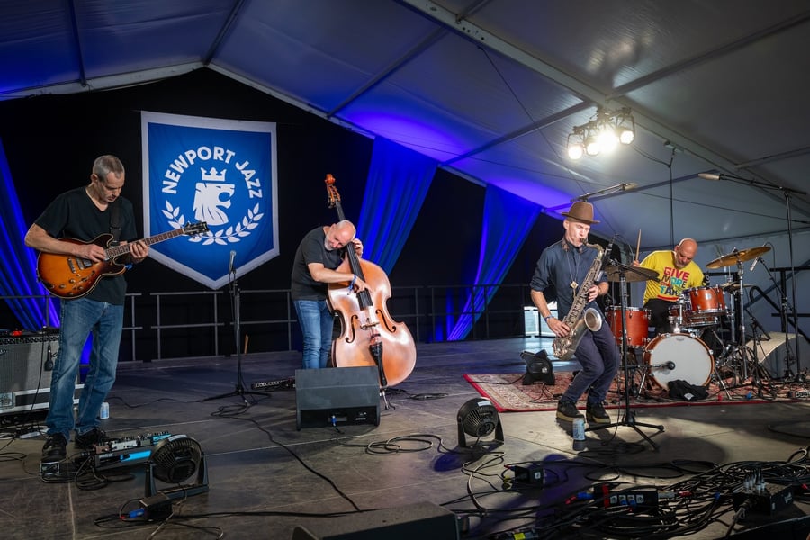 The Bad Plus performing onstage with guitar, double bass, saxophone and drums at Newport Jazz Festival.
